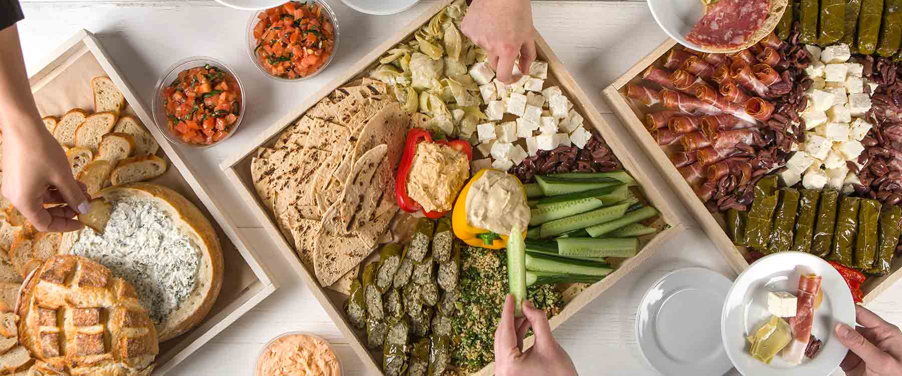 Hands filling plates from party platers